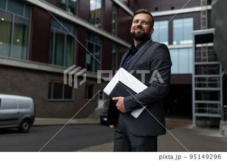 portrait of a successful adult businessman with a laptop in his hands against the background of the portrait of a successful adult businessman with a laptop in his hands against the background of the 95149296
