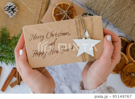 Merry Christmas and Hippy New Year Inspiration joke quote phrase Woman making Box with New Year's gifts, wrapped in craft paper and decorated with fir branch. Holidays and Gifts concept. Handmade Eco 95149767