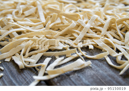 Handmade noodles are dried on a wooden board. Closeup, selective focus Handmade noodles are dried on a wooden board. Closeup, selective focus 95150019