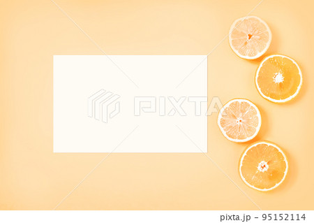 Gently yellow background with white paper sheet and citrus slices 95152114