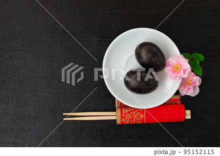 Black eggs, sakura flowers and chopsticks on a dark background 95152115