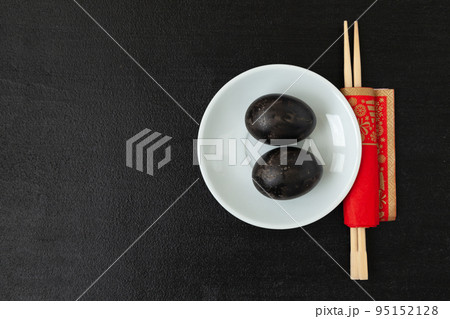Black eggs hard-boiled in sulfuric hot springs and chopsticks on a black background 95152128