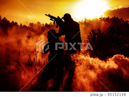 United States Marines in action. Military action, desert battlefield, smoke grenades., fire and explosions. Sun setting, dark silhouettes in the desert 95152139