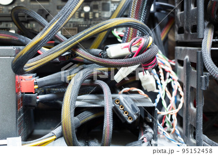 Very dirty wires, connectors and plugs in the computer. Old multi-colored wires in a braided wrapper. Stranded electrical wire in electronic equipment. Service workshop for electronics repair. 95152458