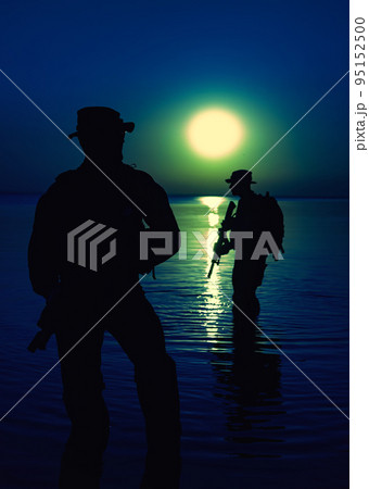 Army soldiers with rifles moon night silhouette in action during raid crossing river in the water, two militants with rifles at night Army soldiers with rifles moon night silhouette in action during raid crossing river in the water, two militants with rifles at night 95152500