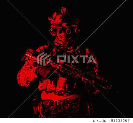 Half length, low key studio shoot of army soldier, marine infantryman in mask, camo uniform, equipped modern ammunition, armed service rifle standing in darkness with night vision device on helmet 95152567