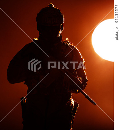 Army soldier in Protective Combat Uniform holding Special Operations Forces Combat Assault Rifle operating at sunset lit by evening sun Army soldier in Protective Combat Uniform holding Special Operations Forces Combat Assault Rifle operating at sunset lit by evening sun 95152577