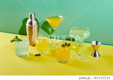 Multi-colored cocktails in glasses of different shapes on colored backgrounds with hard shadows 95153514