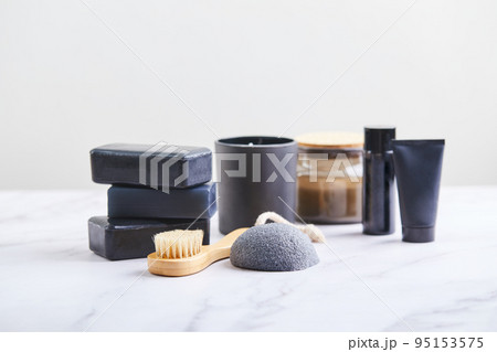 Three pieces of black charcoal soap, Konjac sponge, beauty care products, candles and brushes for washing and massage on marble background Three pieces of black charcoal soap, Konjac sponge, beauty care products, candles and brushes for washing and massage on marble background 95153575
