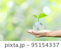 Young plant on crystal globe in hand with green background, concept for eco friendly business, green energy and climate change. 95154337