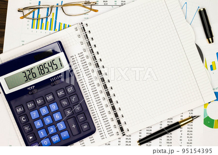 Top view office table desk. Financial report. Flat lay. Workspace with Business office supplies, numbers and empty sheet of paper, diagrams, pen, glasses, calculator. Copy space for text. Top view 95154395