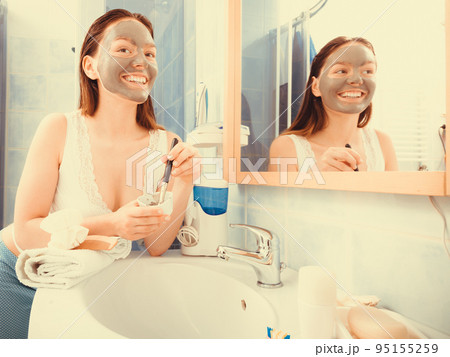 Woman applying mud facial mask Woman applying mud facial mask 95155259