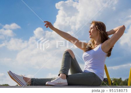 Girl wearing trousers and sneakers pointing outdoor 95158075