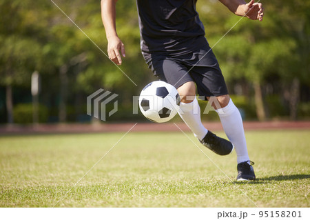 close-up shot of feet of asian soccer player handling the ball on football field close-up shot of feet of asian soccer player handling the ball on football field 95158201