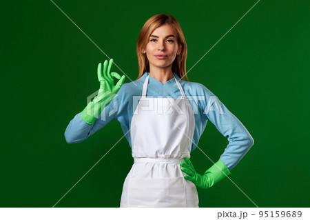 smiling blonde woman in rubber gloves showing ok 95159689