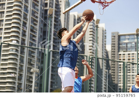 young asian basketball player going up for a layup while opponent playing defense young asian basketball player going up for a layup while opponent playing defense 95159765