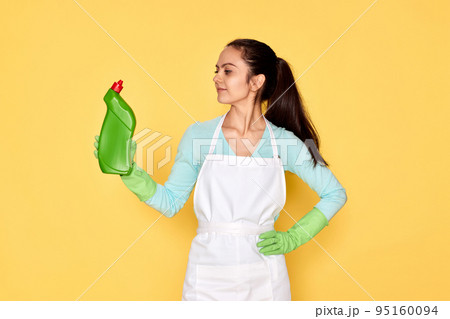 woman in gloves and cleaner apron holding bottle of detergent woman in gloves and cleaner apron holding bottle of detergent 95160094