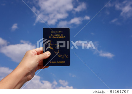 The hand holds the passport of El Salvador against the sky The hand holds the passport of El Salvador against the sky 95161707