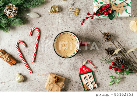 Flat lay of red cup of coffee. Top view of gray background with mug of hot drink, lollipop, gift, fir tree branch, pine cone and Christmas decoration 95162253