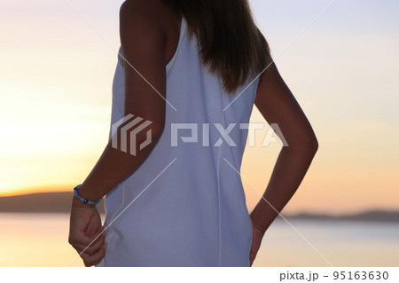 夕暮れのビーチを歩く白い服の女性 夕暮れのビーチを歩く白い服の女性 95163630