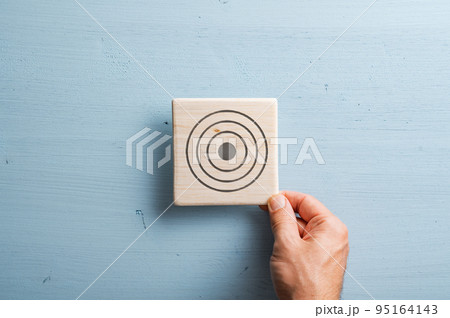 Wooden tile with a target symbol drawn on it 95164143
