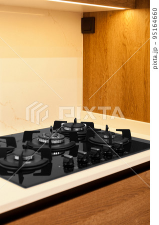 Modern brown wood oak kitchen cabinet equipment, white granite countertops and glass gas stove in a home Modern brown wood oak kitchen cabinet equipment, white granite countertops and glass gas stove in a home 95164660