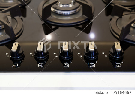 Modern kitchen and black glass ceramic built-in gas oven button detail Modern kitchen and black glass ceramic built-in gas oven button detail 95164667