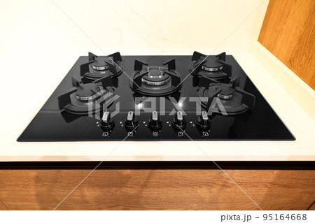 Modern brown wood oak kitchen cabinet equipment, white granite countertops and glass gas stove in a home Modern brown wood oak kitchen cabinet equipment, white granite countertops and glass gas stove in a home 95164668