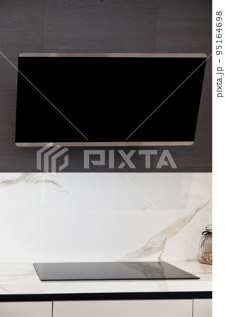 Modern gray white lacquer wood kitchen cabinet and black electric stove and hood on white granite countertop Modern gray white lacquer wood kitchen cabinet and black electric stove and hood on white granite countertop 95164698