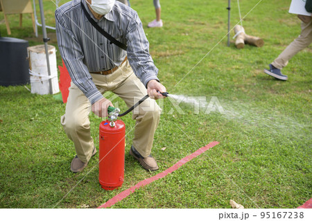 防災イベントで消化器を使う訓練に参加した男性 95167238