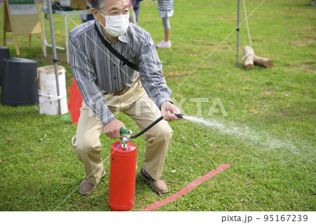 防災イベントで消化器を使う訓練に参加した男性 95167239