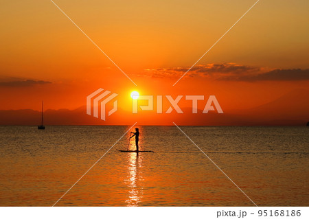 逗子海岸の夕暮れ、夕焼けの中SUPを楽しむ若者のシルエット 逗子海岸の夕暮れ、夕焼けの中SUPを楽しむ若者のシルエット 95168186