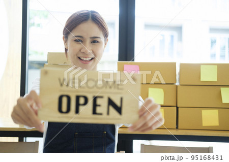 Female online business owner holding welcome, open sign. Female online business owner holding welcome, open sign. 95168431