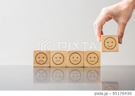 Man hand holding emotion face block. Customer choose Emoticon for user reviews. Service rating, ranking, customer review, satisfaction, evaluation and feedback concept Man hand holding emotion face block. Customer choose Emoticon for user reviews. Service rating, ranking, customer review, satisfaction, evaluation and feedback concept 95170430