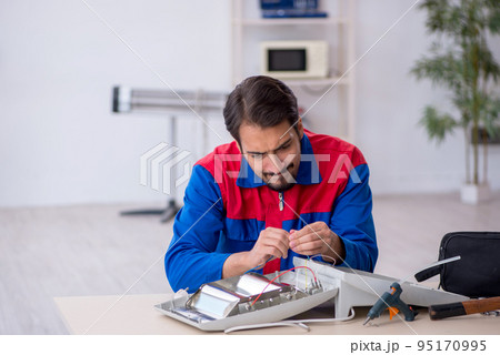 Young male repairman repairing heater 95170995
