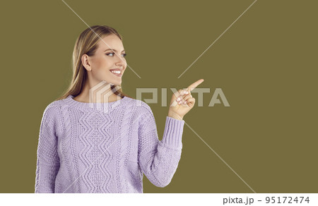 Smiling beautiful woman with index finger pointing sideways on place for copy space. 95172474
