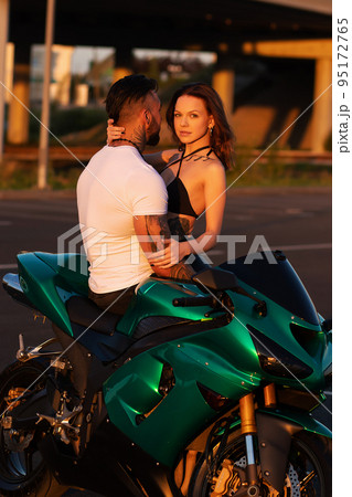 Couple hugging near motorbike at sunset Couple hugging near motorbike at sunset 95172765