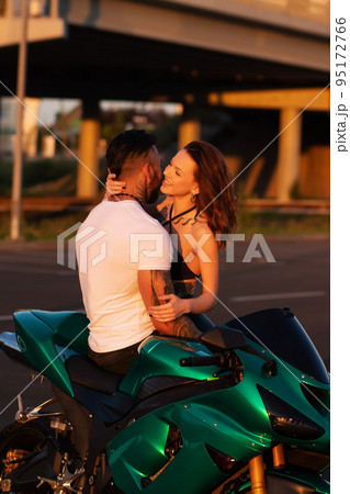 Couple hugging near motorbike at sunset Couple hugging near motorbike at sunset 95172766