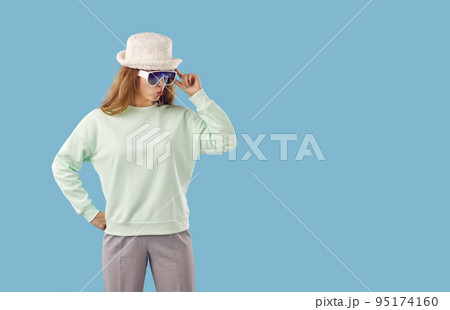 Puzzled woman on light blue background is looking at copy space through sunglasses. 95174160