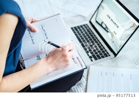 Job interview, Finding New Job. Young woman writing in Planner diary notes about job interview sitting near laptop on the bed at home Job interview, Finding New Job. Young woman writing in Planner diary notes about job interview sitting near laptop on the bed at home 95177513