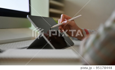 Close-up, A hipster female graphic designer sketching on her digital tablet at her desk. Close-up, A hipster female graphic designer sketching on her digital tablet at her desk. 95178448