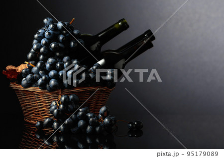 Red wine and blue grapes on a black reflective background. Red wine and blue grapes on a black reflective background. 95179089