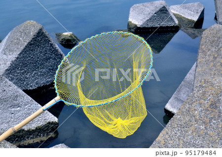 手長エビが掛かった時のためにテトラの上で待機する玉網 手長エビが掛かった時のためにテトラの上で待機する玉網 95179484