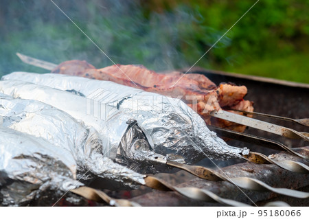 The meat on metal skewers is wrapped in aluminum foil and grilled on charcoal. The meat on metal skewers is wrapped in aluminum foil and grilled on charcoal. 95180066