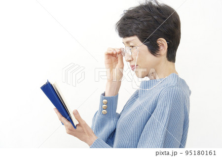 老眼鏡をかけて読書する中年女性 白背景 老眼鏡をかけて読書する中年女性 白背景 95180161