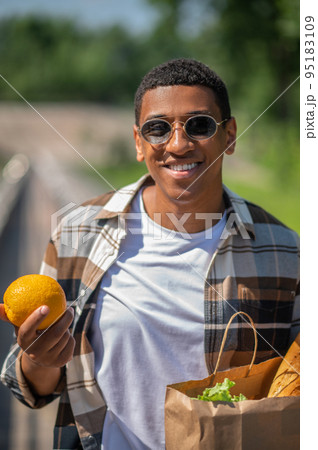 Young dark-skinned man with a paper bag of food 95183109