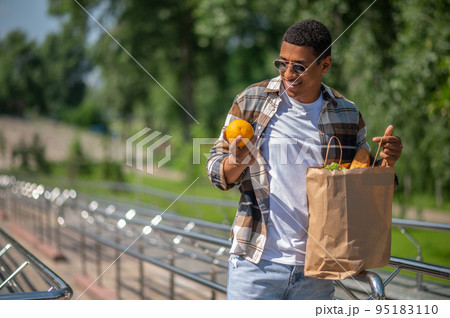 Young dark-skinned man with a paper bag of food 95183110