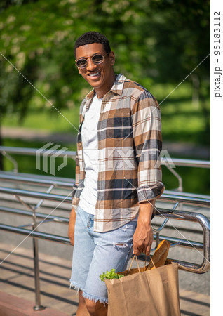 Young dark-skinned man with a paper bag of food 95183112
