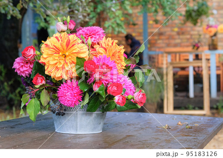 Roses, asters, dahilia in vase in the garden on a wooden table. Sunny day. Bright rural design. Roses, asters, dahilia in vase in the garden on a wooden table. Sunny day. Bright rural design. 95183126