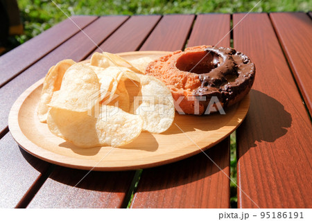 キャンプで食べるチョコオールドファッションドーナツとポテトチップス 95186191